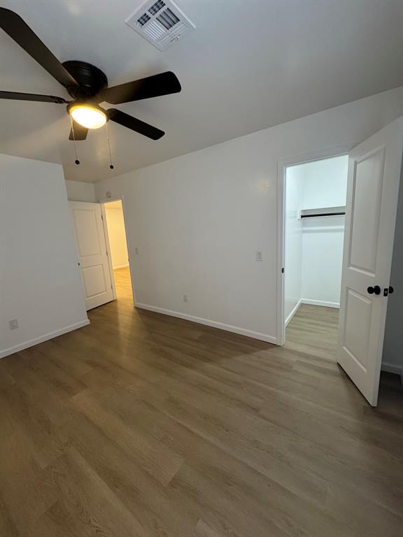 unfurnished bedroom featuring a ceiling fan, wood finished floors, visible vents, and baseboards