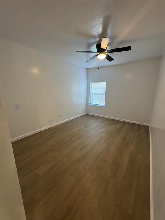 empty room featuring ceiling fan, baseboards, and wood finished floors