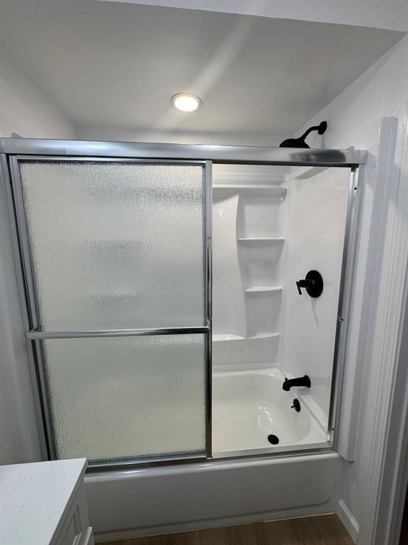 bathroom with enclosed tub / shower combo, vanity, and wood finished floors