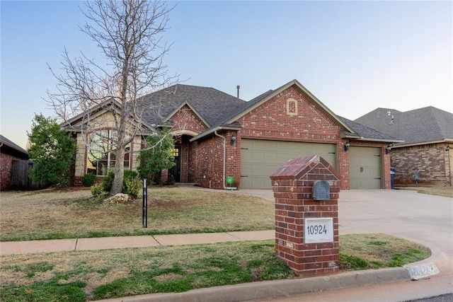 view of front of house featuring brick siding, roof with shingles, a garage, driveway, and a front lawn