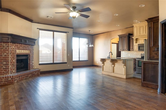 kitchen with stainless steel appliances, a fireplace, visible vents, a kitchen breakfast bar, and open floor plan