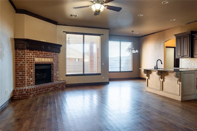 unfurnished living room featuring ornamental molding, visible vents, a sink, and a fireplace