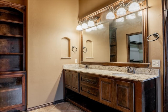 full bath with double vanity, baseboards, a sink, and tile patterned floors