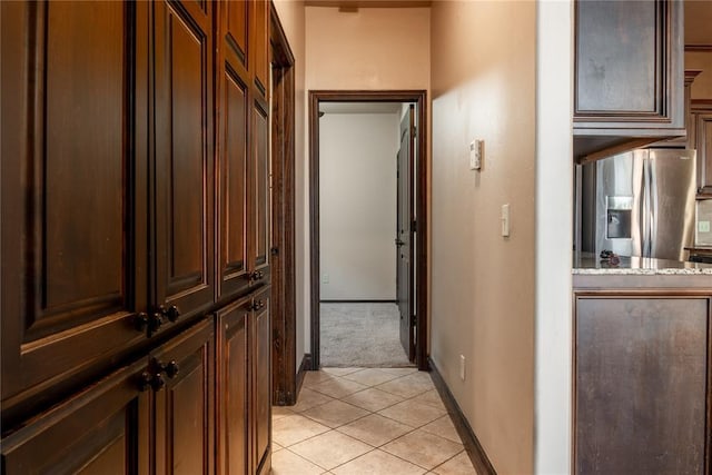 corridor featuring light colored carpet, baseboards, and light tile patterned floors