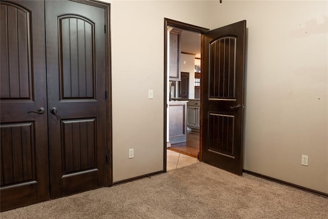 unfurnished bedroom with light carpet and baseboards