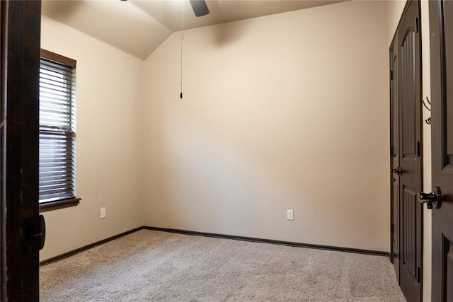 carpeted spare room with vaulted ceiling, a ceiling fan, and baseboards