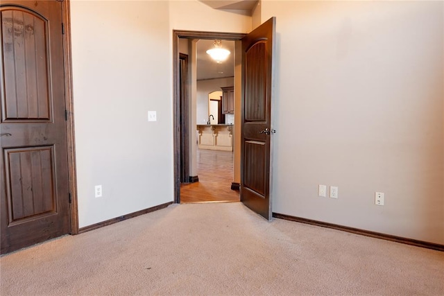 unfurnished bedroom featuring light colored carpet and baseboards