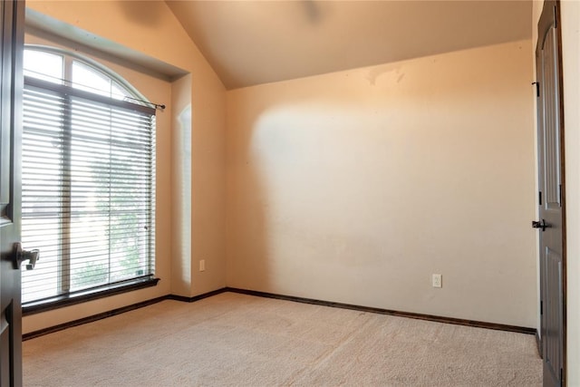 carpeted spare room with baseboards and vaulted ceiling