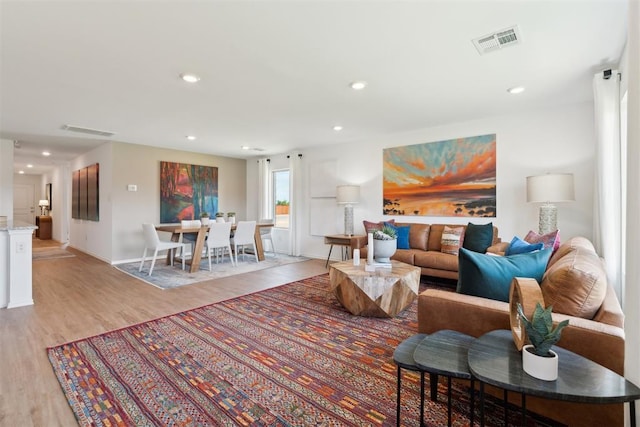 living room featuring light wood-type flooring, visible vents, and recessed lighting