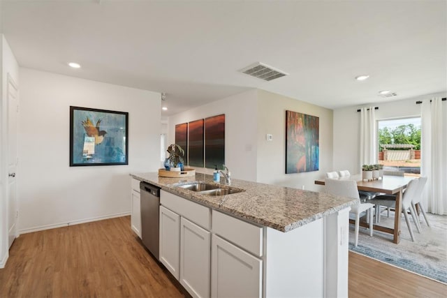 kitchen with visible vents, dishwasher, light wood-style flooring, light stone countertops, and a sink