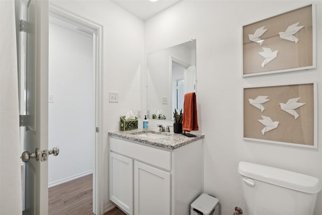 half bath with wood finished floors, vanity, and toilet