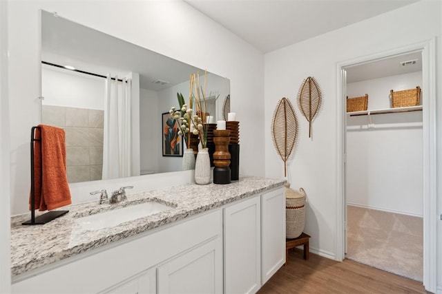 bathroom with visible vents, vanity, baseboards, and wood finished floors