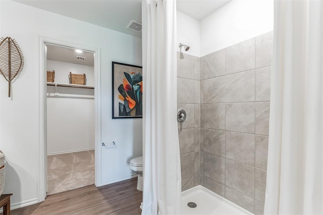 bathroom with toilet, wood finished floors, visible vents, baseboards, and a stall shower