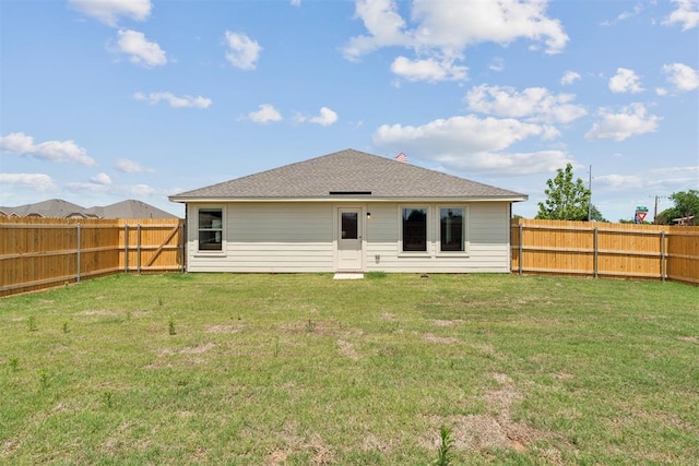 back of property featuring a yard, a shingled roof, and a fenced backyard