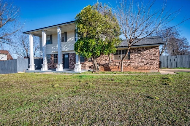 back of house with a yard, brick siding, and fence