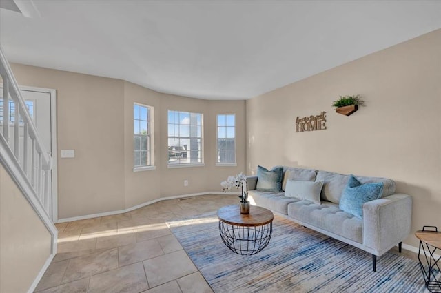 living area featuring tile patterned flooring, stairs, and baseboards