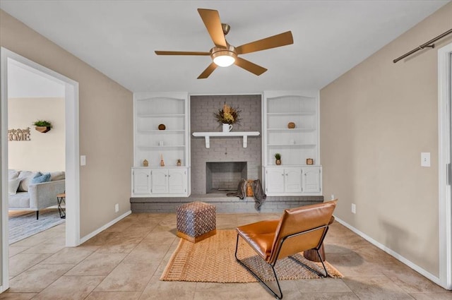 living area featuring a brick fireplace, built in features, baseboards, and ceiling fan