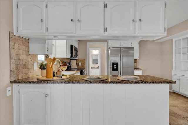 kitchen with dark stone counters, decorative backsplash, appliances with stainless steel finishes, a peninsula, and white cabinets