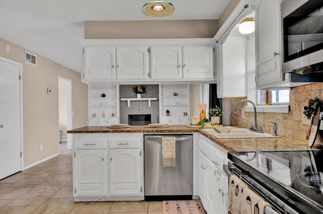 kitchen featuring visible vents, a sink, appliances with stainless steel finishes, a peninsula, and white cabinets