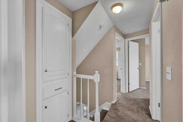 corridor featuring an upstairs landing, baseboards, and carpet floors