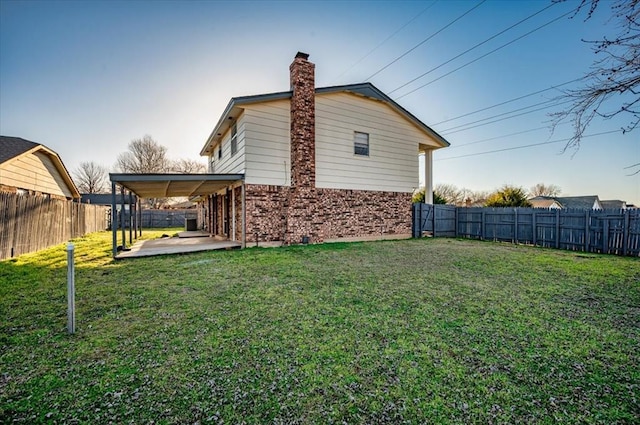 rear view of property featuring a lawn, a chimney, a fenced backyard, and brick siding