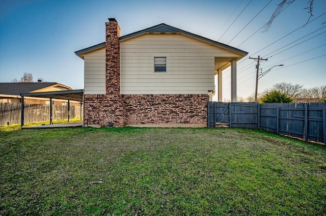 rear view of house featuring a lawn, a chimney, a fenced backyard, and brick siding