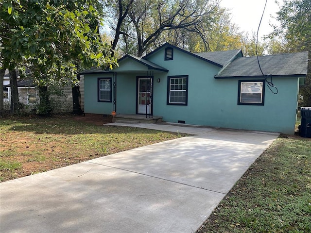 ranch-style house with driveway, a front lawn, a shingled roof, and stucco siding