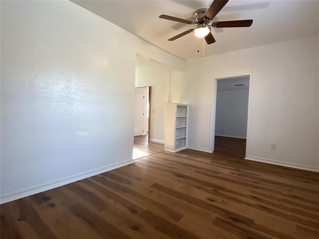 empty room featuring dark wood finished floors, a ceiling fan, and baseboards