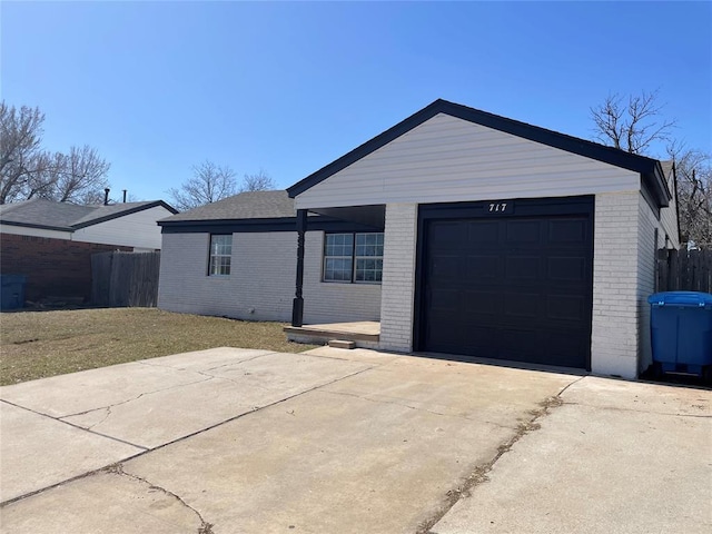 exterior space featuring brick siding, an attached garage, driveway, and fence