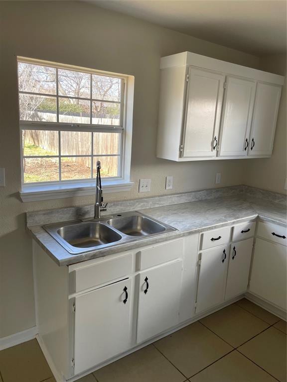 kitchen featuring light tile patterned floors, white cabinetry, light countertops, and a sink