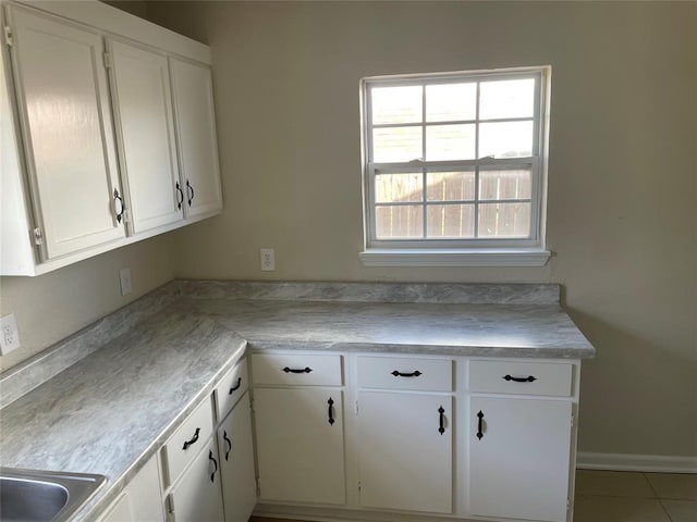 kitchen featuring white cabinetry, light countertops, tile patterned flooring, and a sink