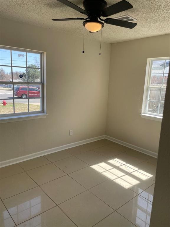 tiled spare room with a ceiling fan, baseboards, and a textured ceiling