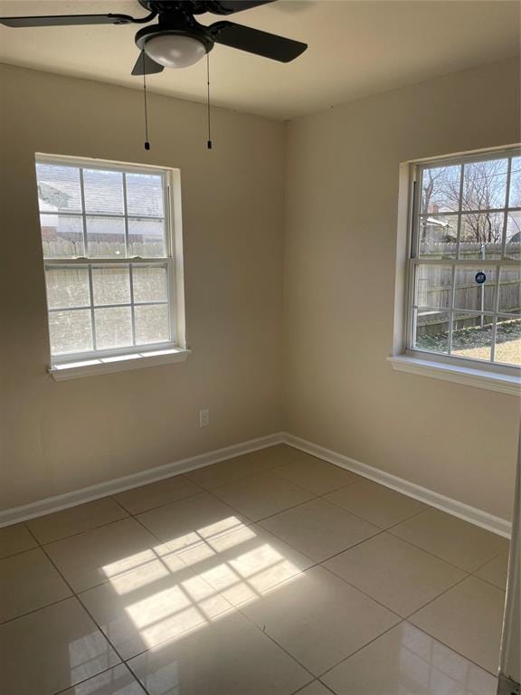 unfurnished room with baseboards, ceiling fan, and tile patterned flooring