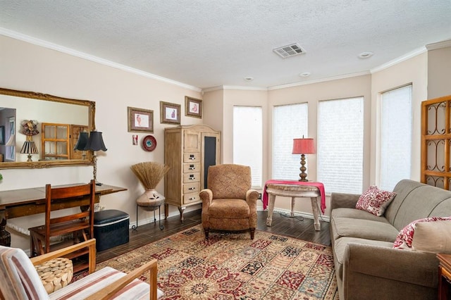 living area featuring visible vents, ornamental molding, a textured ceiling, wood finished floors, and baseboards