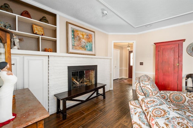 living room featuring dark wood finished floors, crown molding, and a fireplace