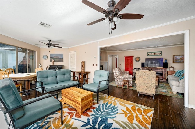 living room featuring wood finish floors, visible vents, a ceiling fan, a textured ceiling, and crown molding