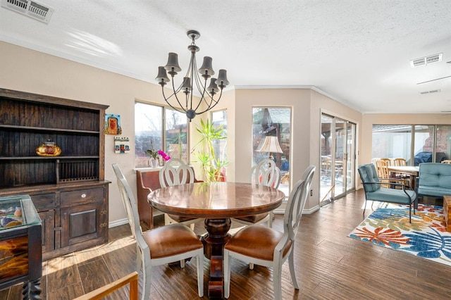 dining area with a textured ceiling, wood finished floors, visible vents, and a chandelier