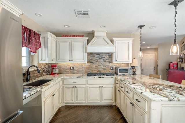 kitchen with visible vents, a peninsula, a sink, stainless steel appliances, and custom range hood