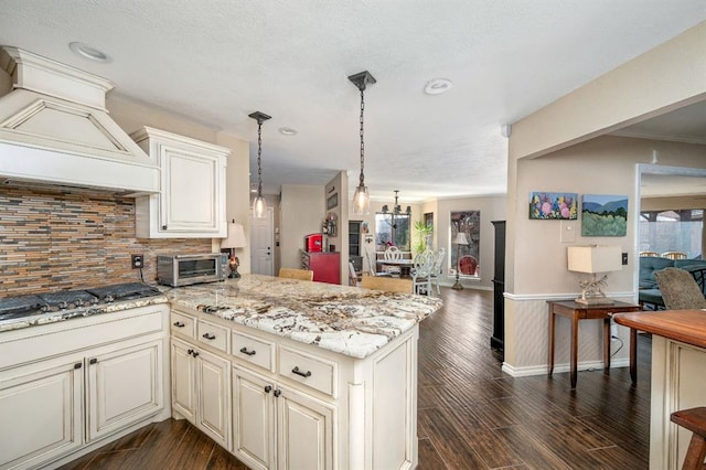 kitchen with dark wood-type flooring, backsplash, a toaster, custom exhaust hood, and stainless steel gas cooktop