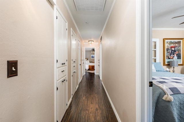 hallway with visible vents, dark wood finished floors, crown molding, baseboards, and a textured wall