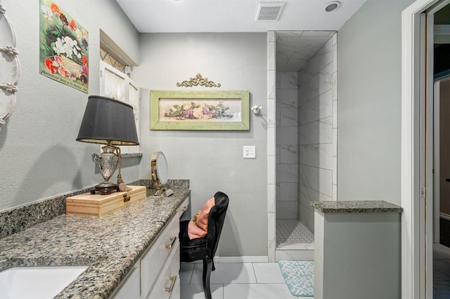 full bathroom with a tile shower, visible vents, vanity, and baseboards