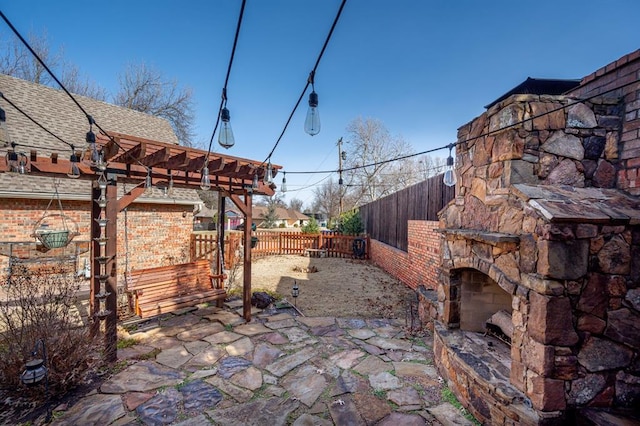 view of patio featuring an outdoor stone fireplace, a fenced backyard, and a pergola