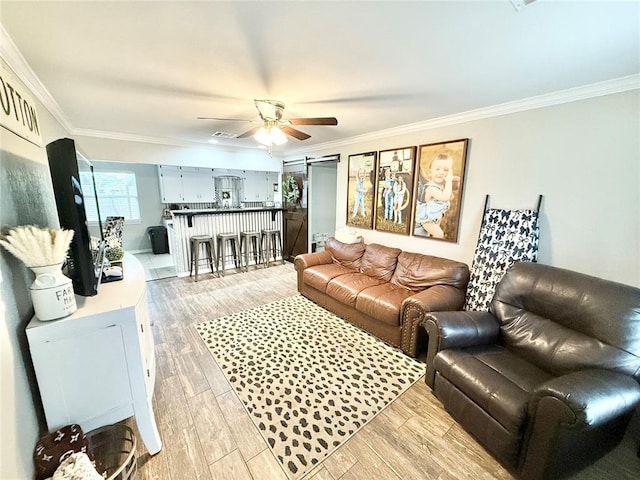 living area with ceiling fan, light wood finished floors, visible vents, and crown molding