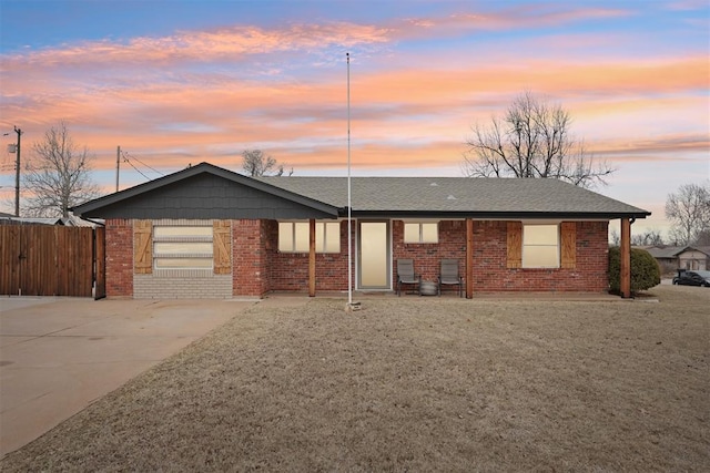 view of front of house featuring an attached garage, brick siding, driveway, roof with shingles, and a front lawn