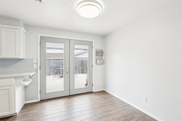 entryway with french doors, light wood-type flooring, and baseboards