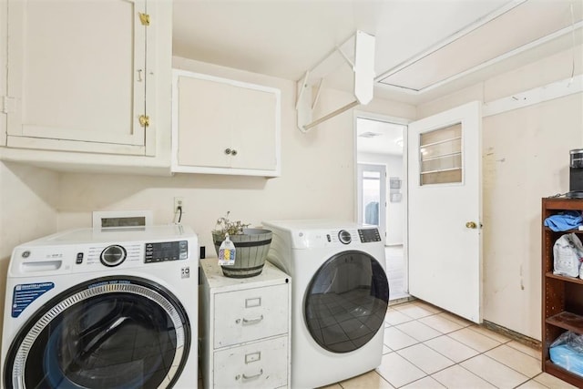 clothes washing area with cabinet space, light tile patterned floors, and washer and clothes dryer