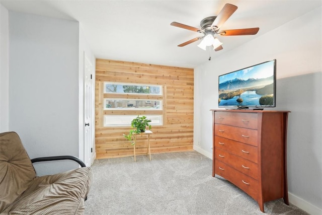 living area with light carpet, baseboards, and wooden walls