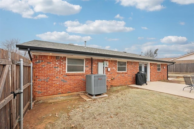 back of property with brick siding, a patio, a lawn, cooling unit, and a fenced backyard