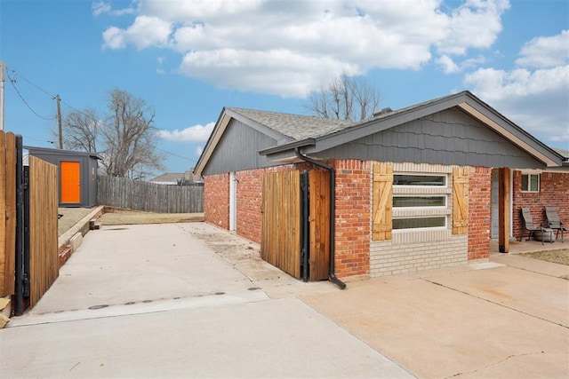 view of side of home with a patio area, fence, and brick siding