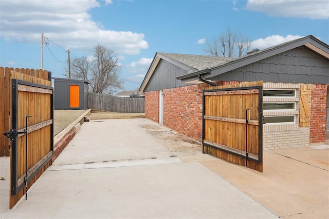 view of home's exterior with a patio area, brick siding, a fenced backyard, and roof with shingles